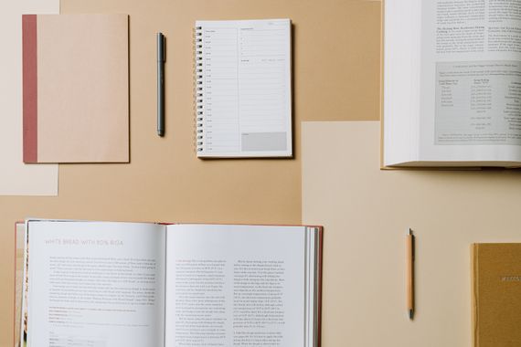 Pessoa folheando livro de receitas aberto sobre mesa enquanto cozinha — organização na cozinha
