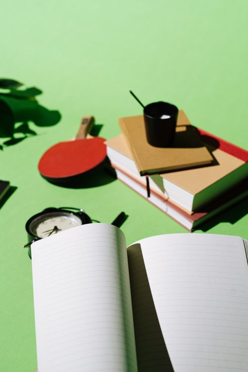Free A creative workspace with an open notebook, books, and supplies on a vibrant green background. Stock Photo