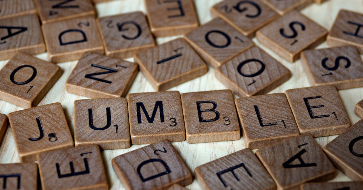 Close-up of scattered Scrabble tiles forming the word 'jumble' on a wooden surface.