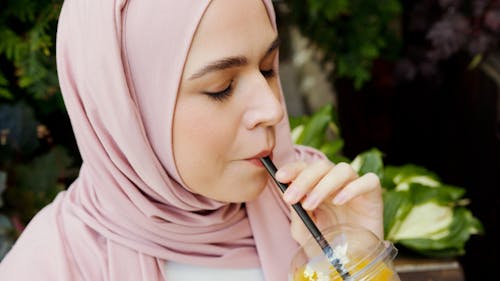 Woman in Pink Hijab Holding Clear Plastic Cup