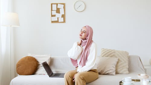 Free Woman in Pink Hijab and White Long Sleeve Shirt Sitting on White Couch Stock Photo