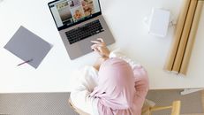 一位女实业家头戴头巾，在现代工作区的笔记本电脑前俯身工作
