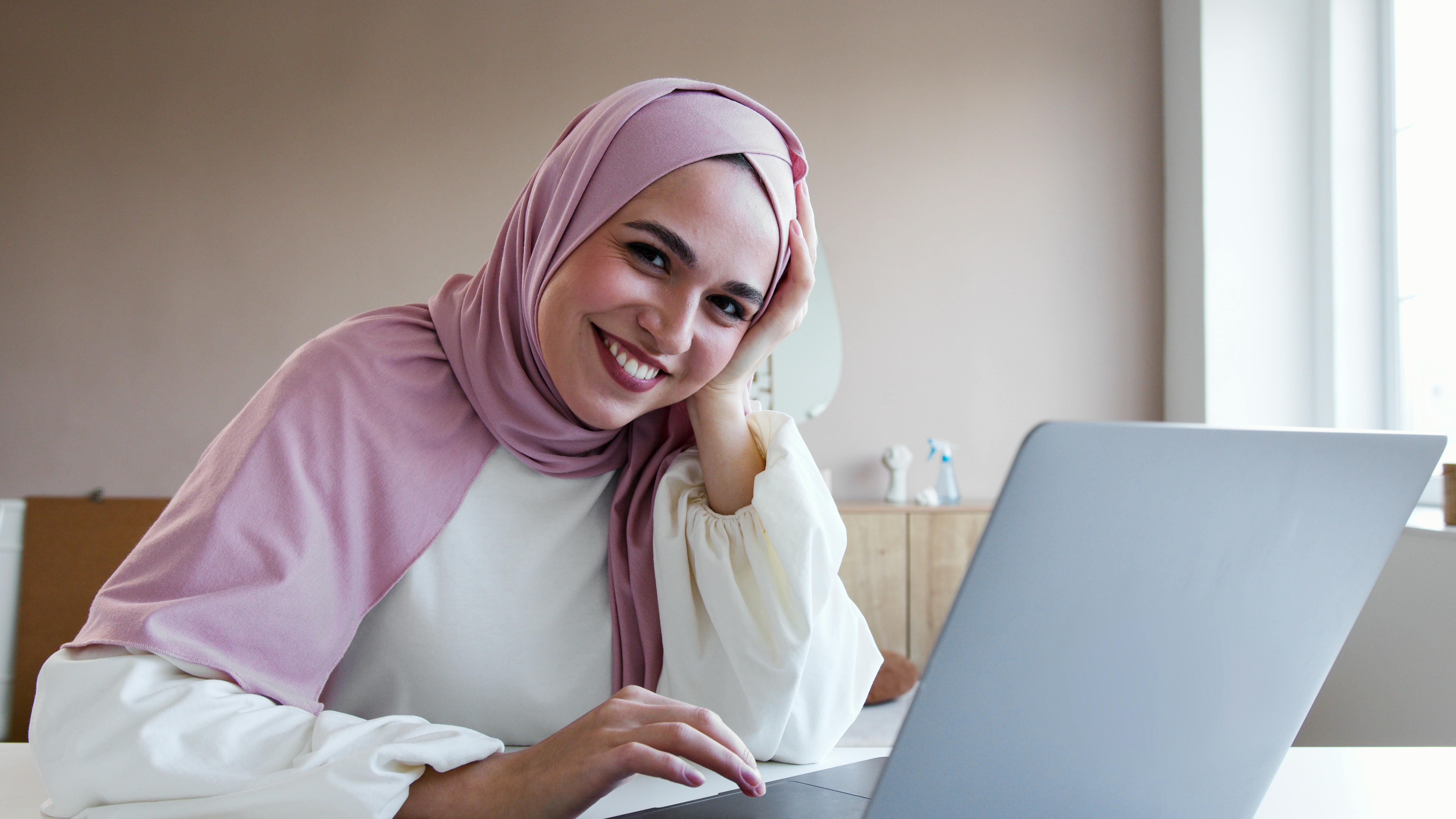 a woman in white long sleeves and pink hijab smiling
