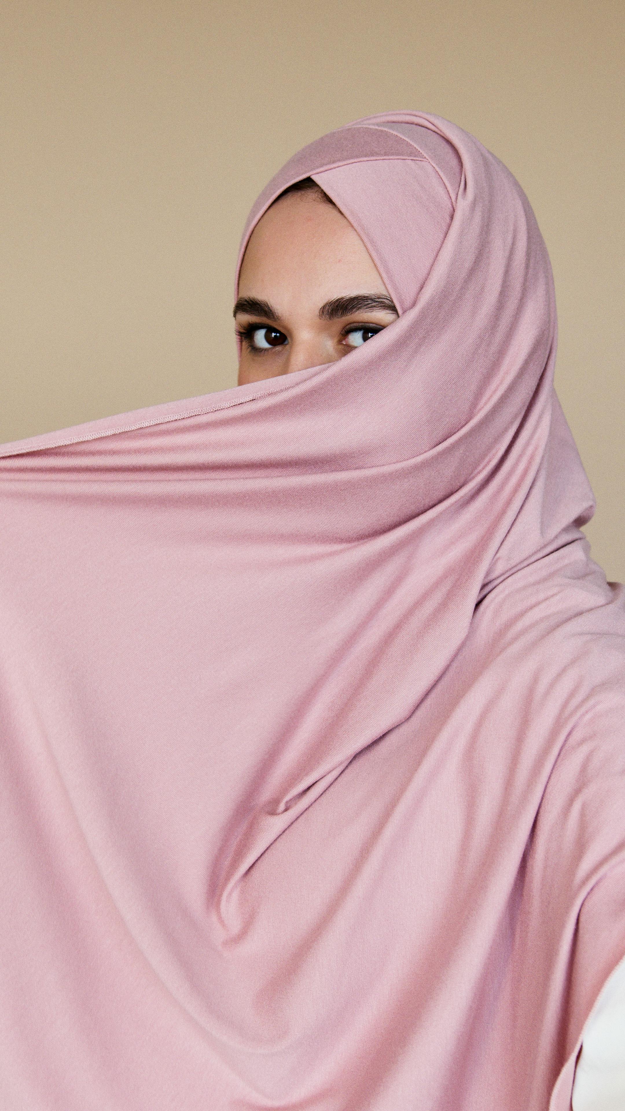 a woman in pink hijab covering her face