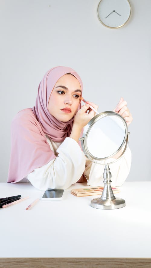A Woman in Pink Hijab Applying Makeup