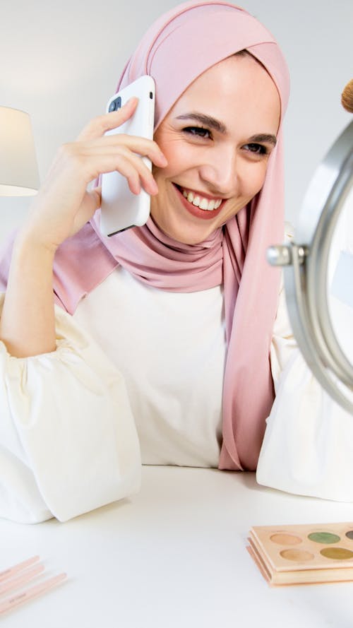 Free A Woman in Pink Hijab Smiling while Talking on the Phone Stock Photo