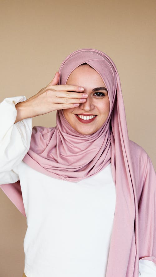 Woman in White Dress and Pink Hijab Smiling and Closing Right Eye