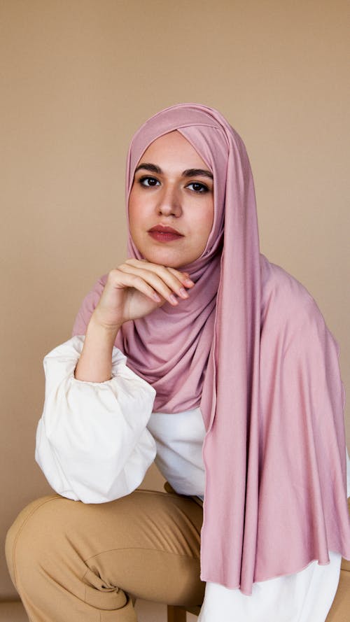 Woman in Pink Hijab and White Long Sleeve Shirt Sitting