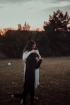 A warm scene of a woman hugging her dog during a beautiful sunset in a fall field.