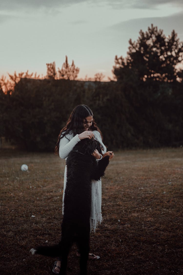 Woman Hugging Dog On Grass Field