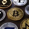 A close-up view of various physical cryptocurrency tokens, including a prominent Zcash coin alongside Bitcoin and Ethereum.