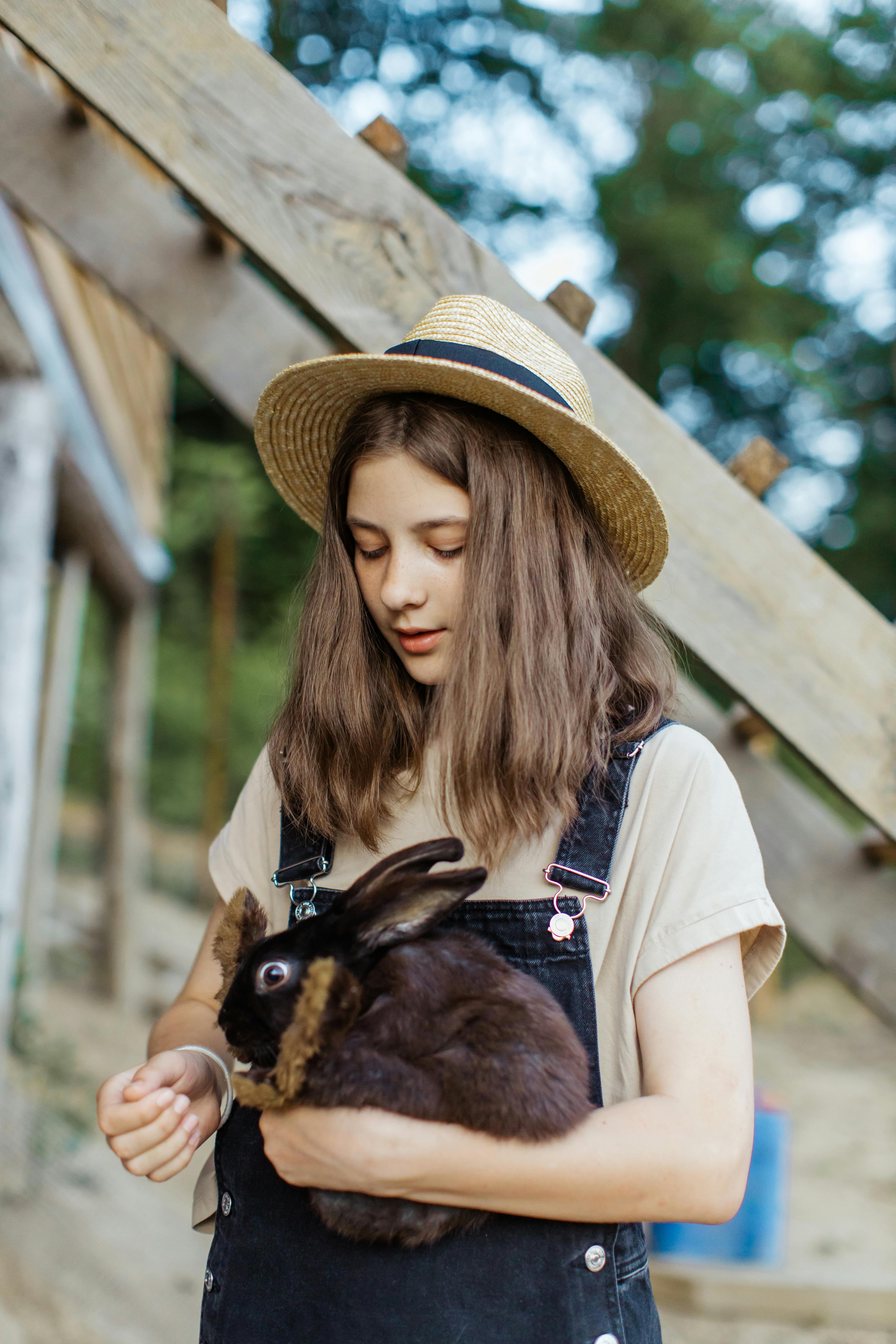 woman in brown hat holding brown animal