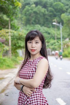 一位穿着方格连衣裙的迷人女子，正走在风景优美的户外道路上