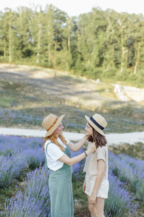 A Mother and Daughter Standing on Lavender Field while Looking at Each Other