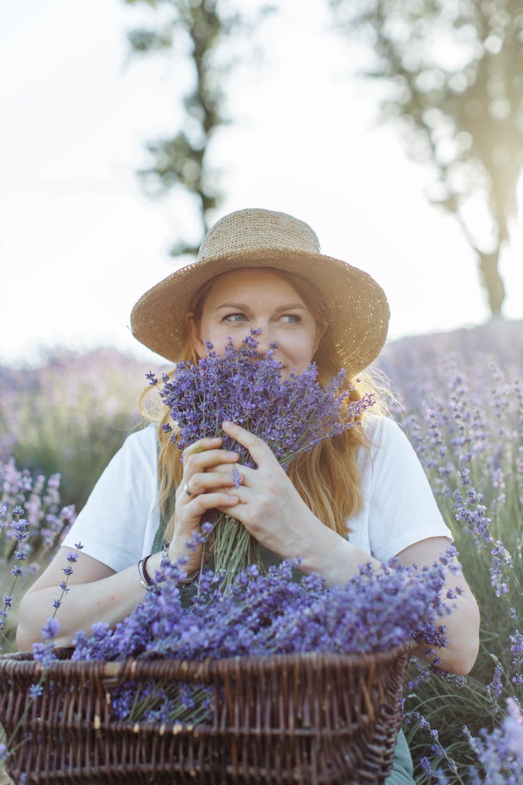 A Woman In White Shirt Holding A Bunch Of Lavender Flowers