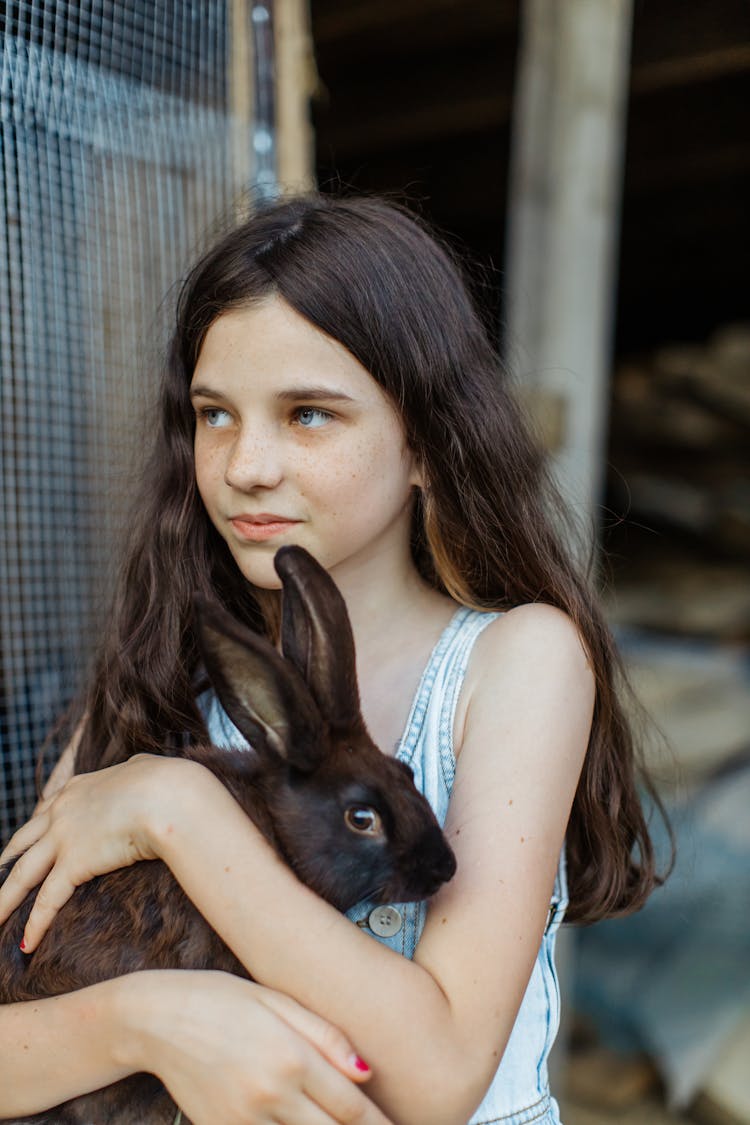 A Girl Carrying Brown Rabbit While Looking Afar