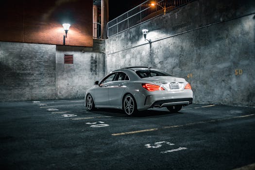 Sleek luxury car illuminated by street lamps in a quiet, urban parking area at night.