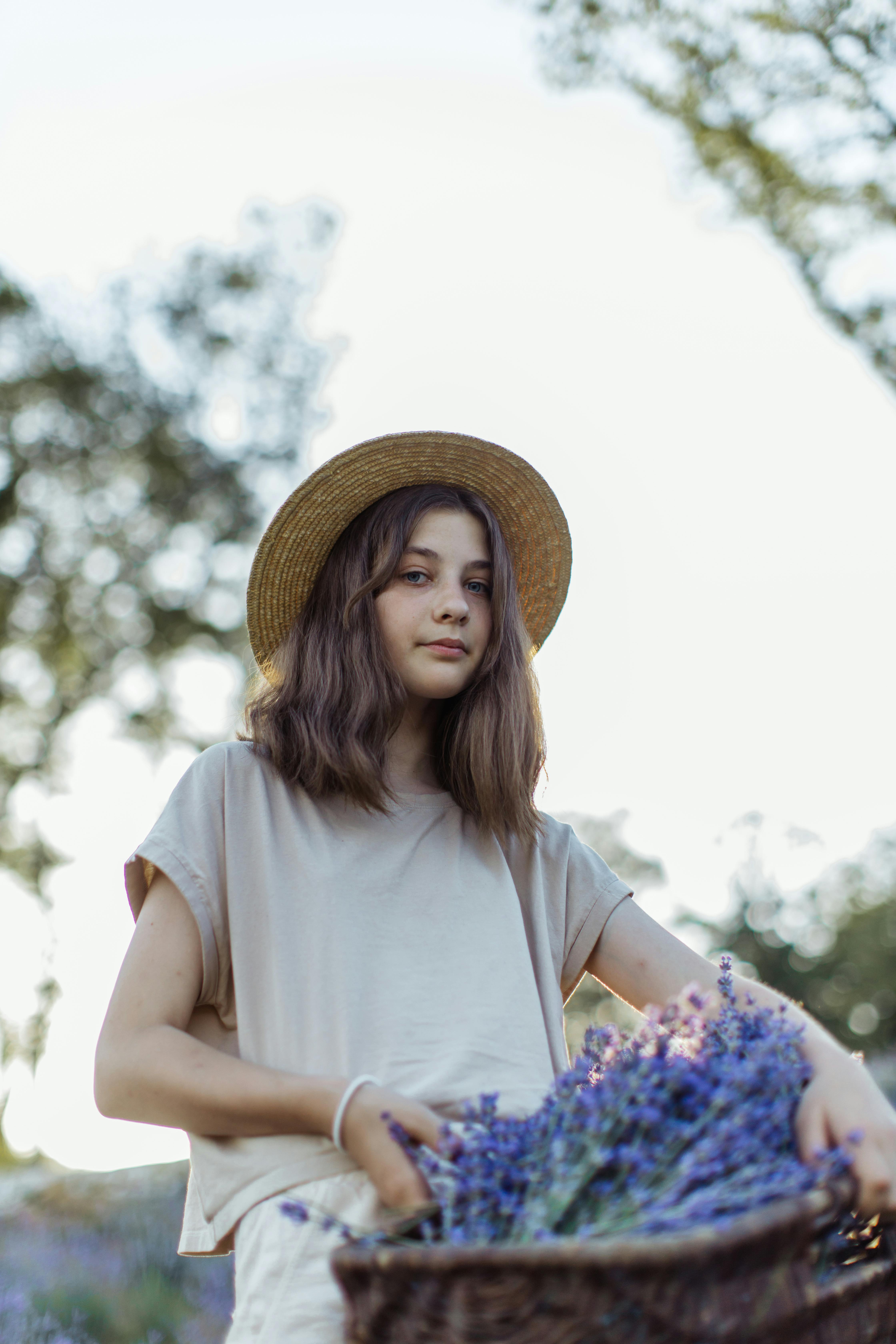 a young girl wearing brown hat carrying basket full of lavender flowers