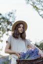 A Young Girl Wearing Brown Hat Carrying Basket Full of Lavender Flowers