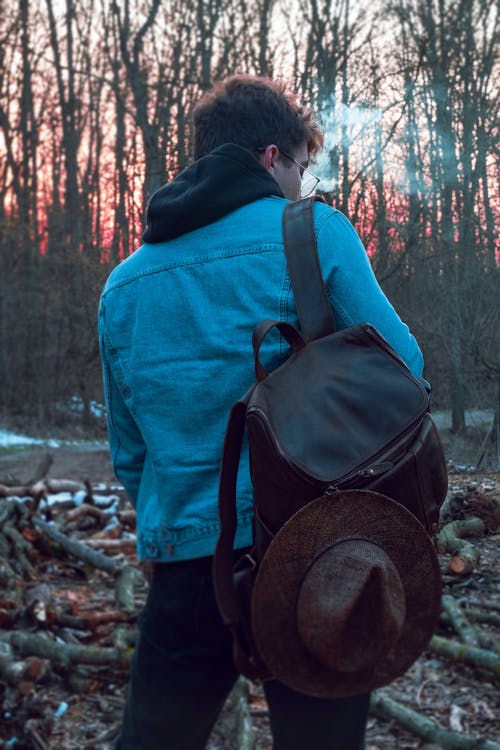 Back View Shot of a Man Carrying Backpack while Standing on the Forest