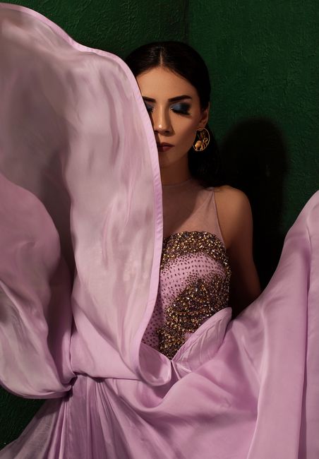 Young female model with bright makeup on closed eyes in trendy apparel on black background
