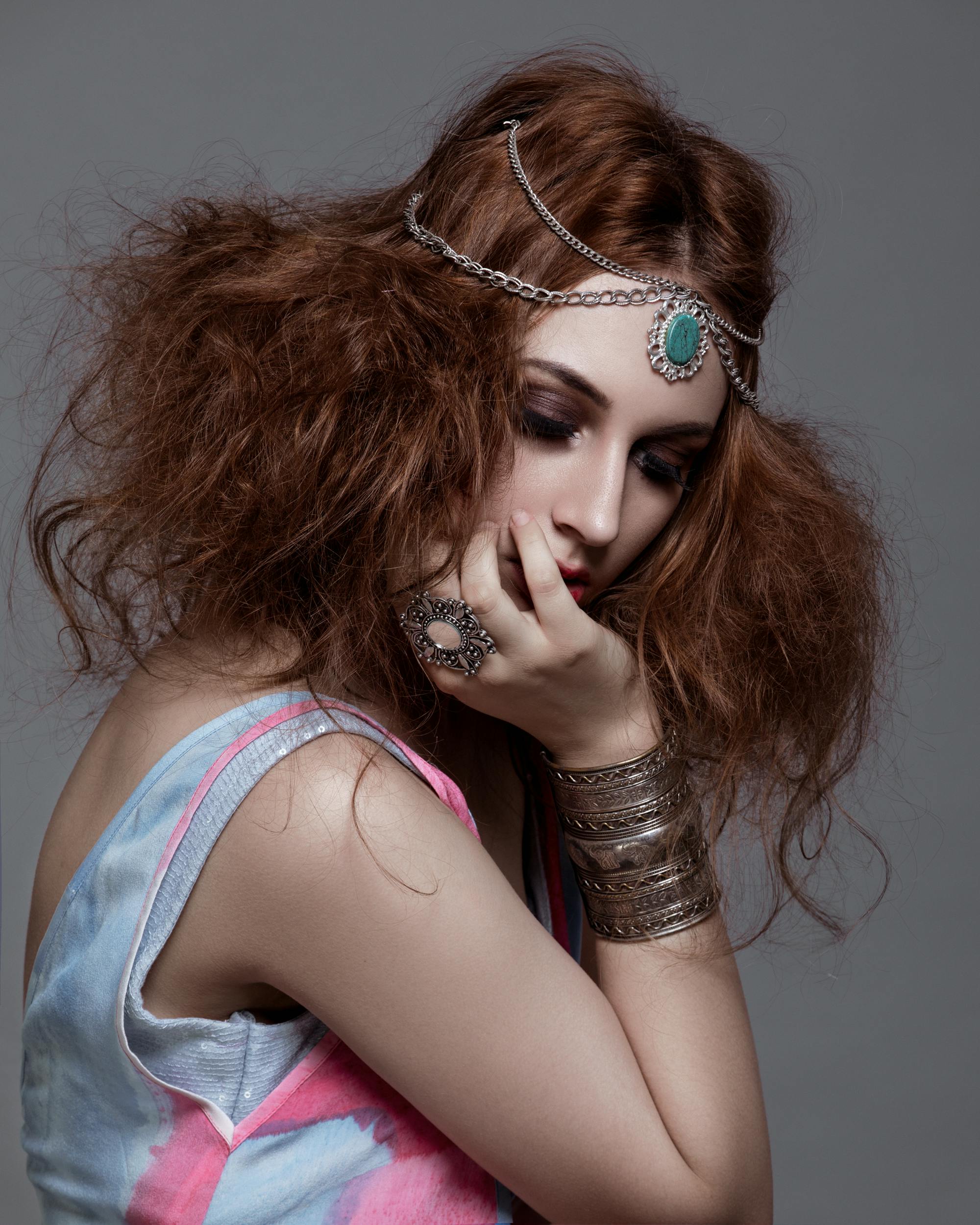 Side view of young trendy female model with makeup and closed eyes touching face