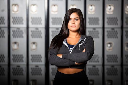 Young woman with long brunette hair in gym locker room, wearing exercise gear.