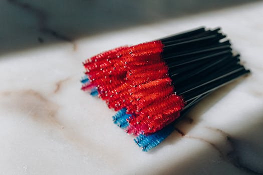 A vibrant set of mascara brushes with red and blue bristles on a marble background.