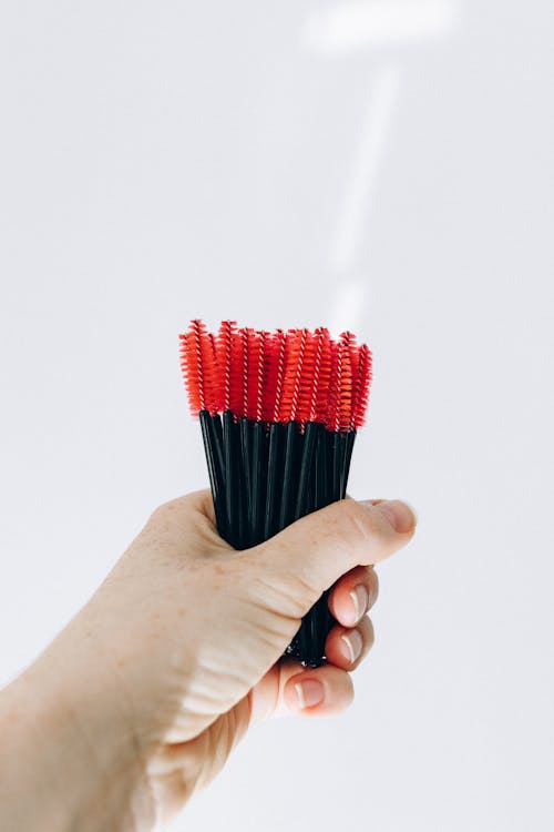 A Person Holding Black and Red Eyelash Brush