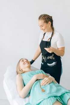 Beautician in apron engages with smiling client in bright spa environment, conveying relaxation.