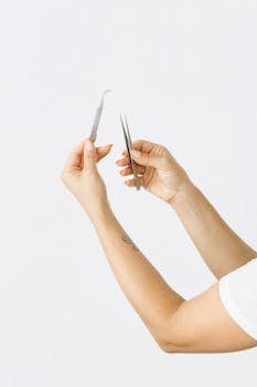 女性手持镊子和剪刀的双手特写，非常适合美容和仪容环境