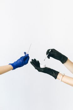 白色背景上，两只戴着手套的手正用工具进行实验特写