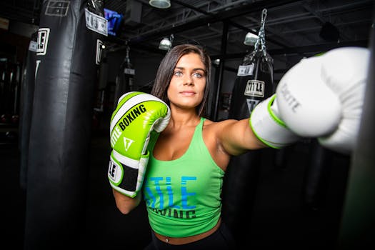 Focused woman in green boxing gloves practicing punches in gym.