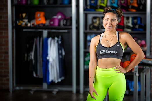 Confident young woman in bright activewear standing in gym with boxing equipment.