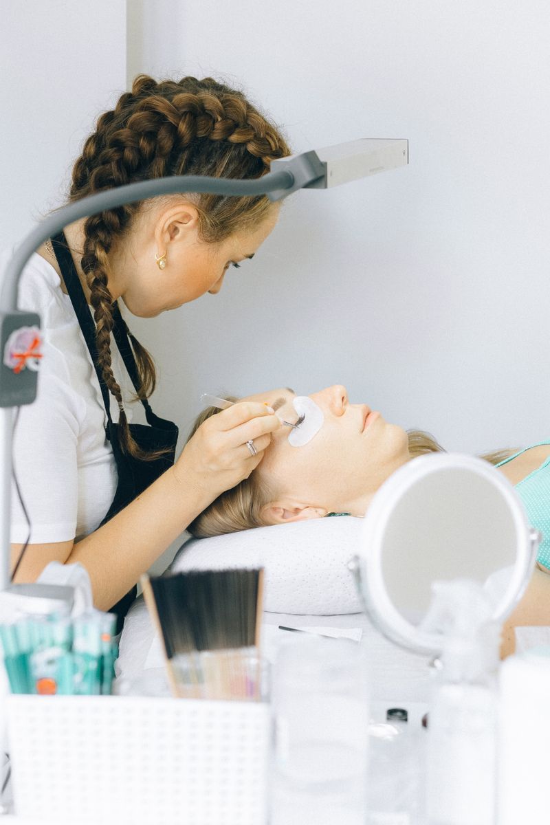 Stylistin setzt einer Kundin einzelne Wimpernextensions