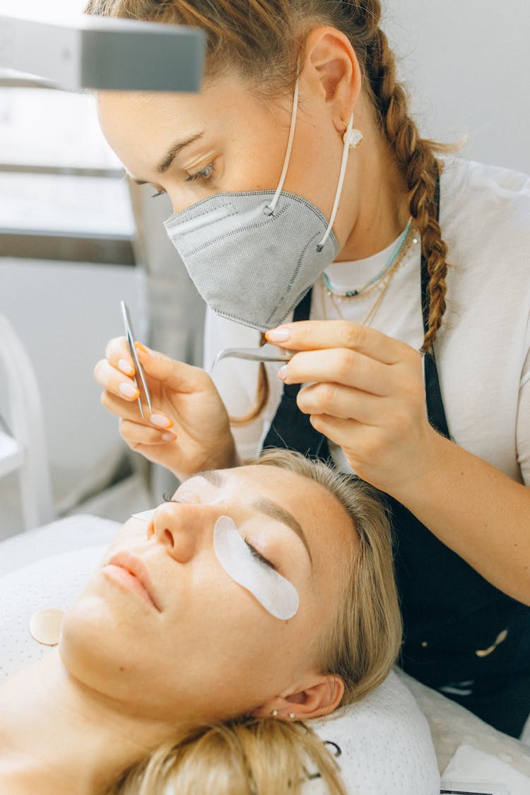 A Woman Putting Cosmetic Lashes On Clients Eye