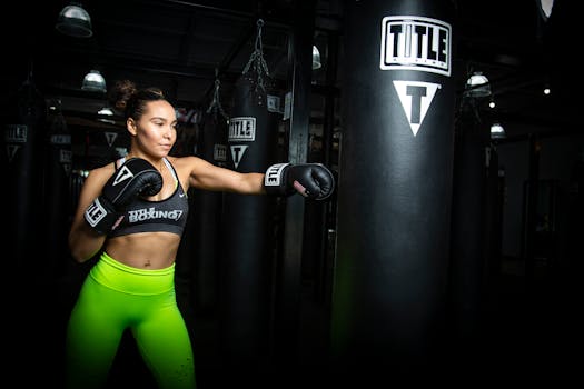 Woman practicing boxing with gloves in a gym setting, showcasing strength and focus.