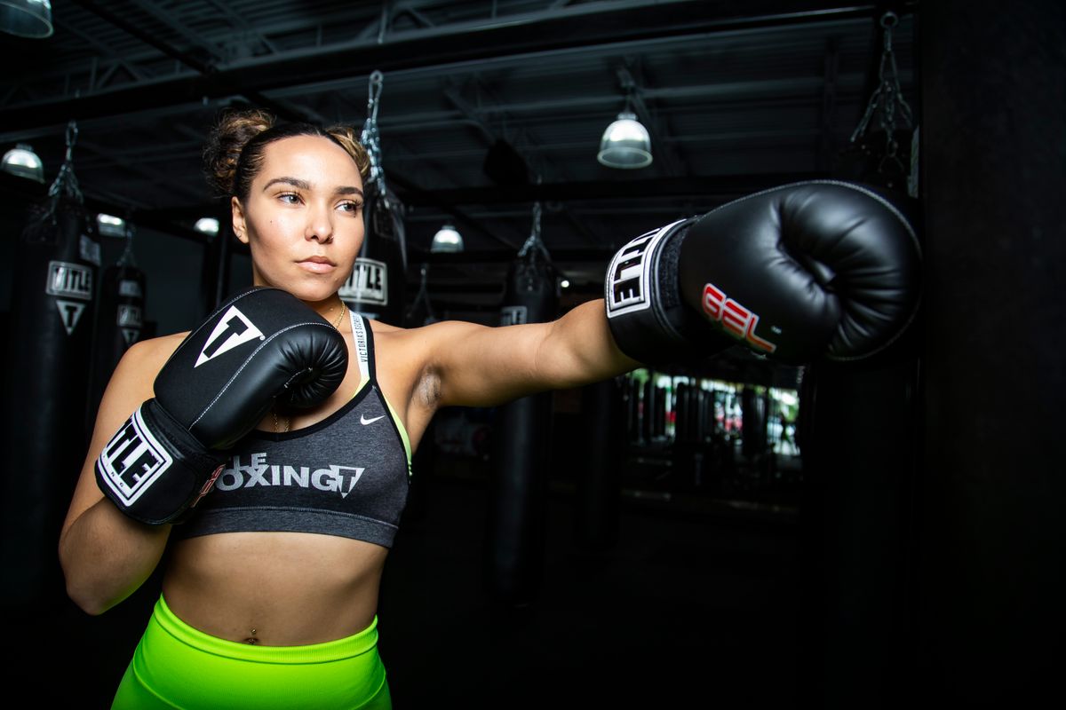 Woman training confidently with boxing gloves in a gym.