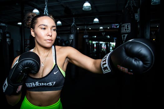 Woman boxer practicing with gloves in a gym, demonstrating focus and strength.