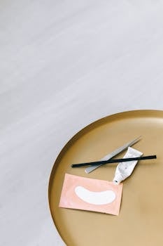 这款极简主义的扁平护肤工具和眼罩置于圆形金色托盘上，是美容与健康概念的理想之选