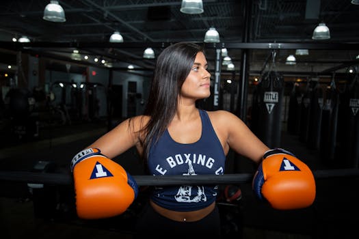 Strong female athlete with boxing gloves ready for training in a modern gym setting.