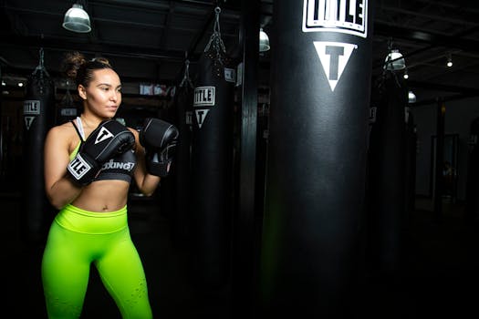 A young woman in vibrant sportswear boxing in a gym environment.