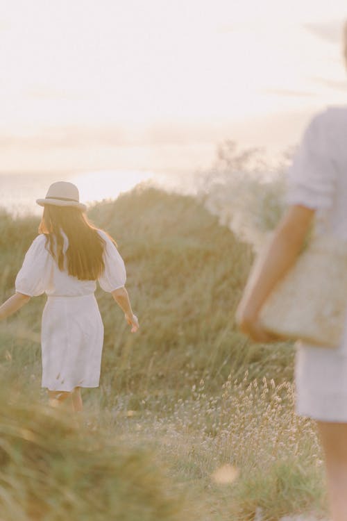 A Woman in White Dress Walking on Grass Field