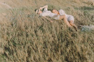 Two Women in White Dress Lying on Brown Grass Field