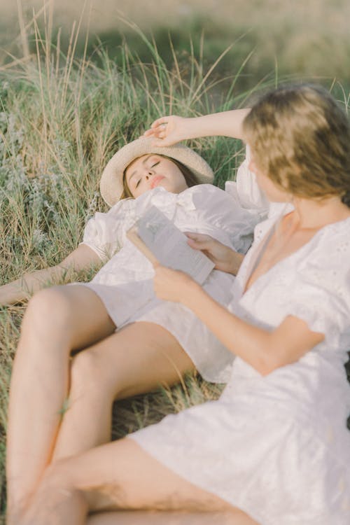 Two Women Reading a Book on Grass Field