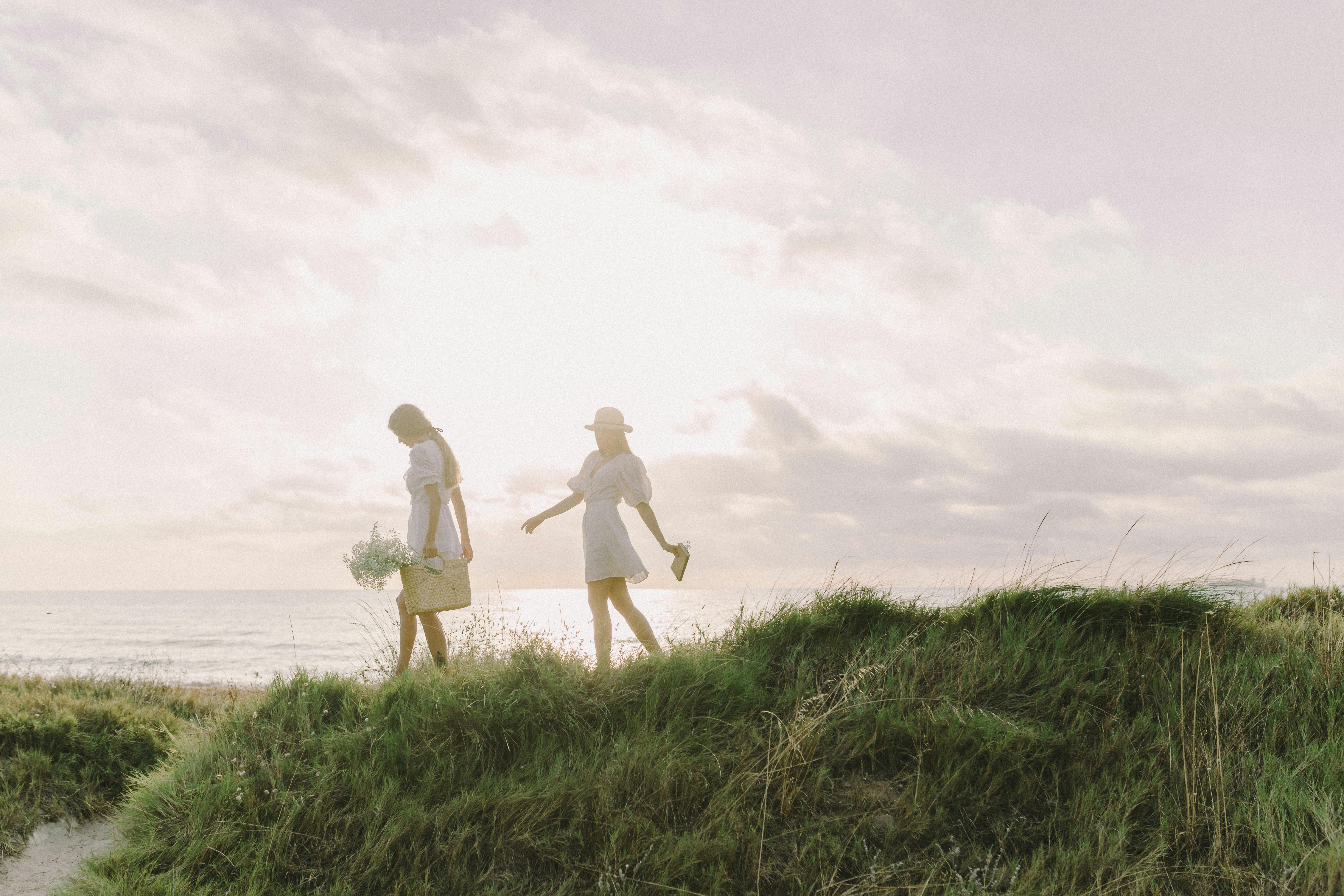 2 women walking on green grass field