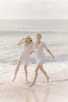两个穿着白色连衣裙的女人，在海滩上享受着阳光明媚的一天，散发着幸福与自由