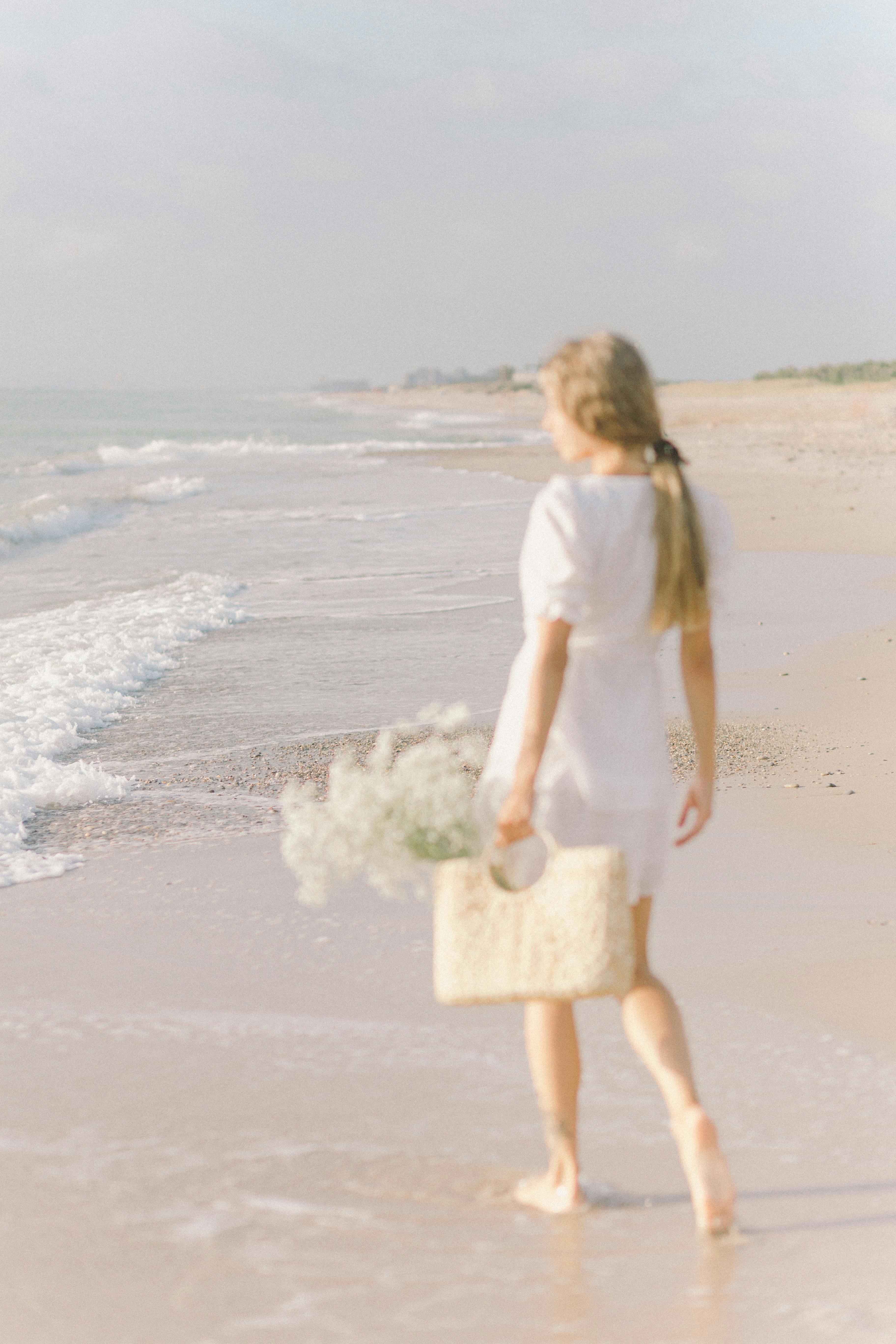 woman in white dress holding basket of flowers