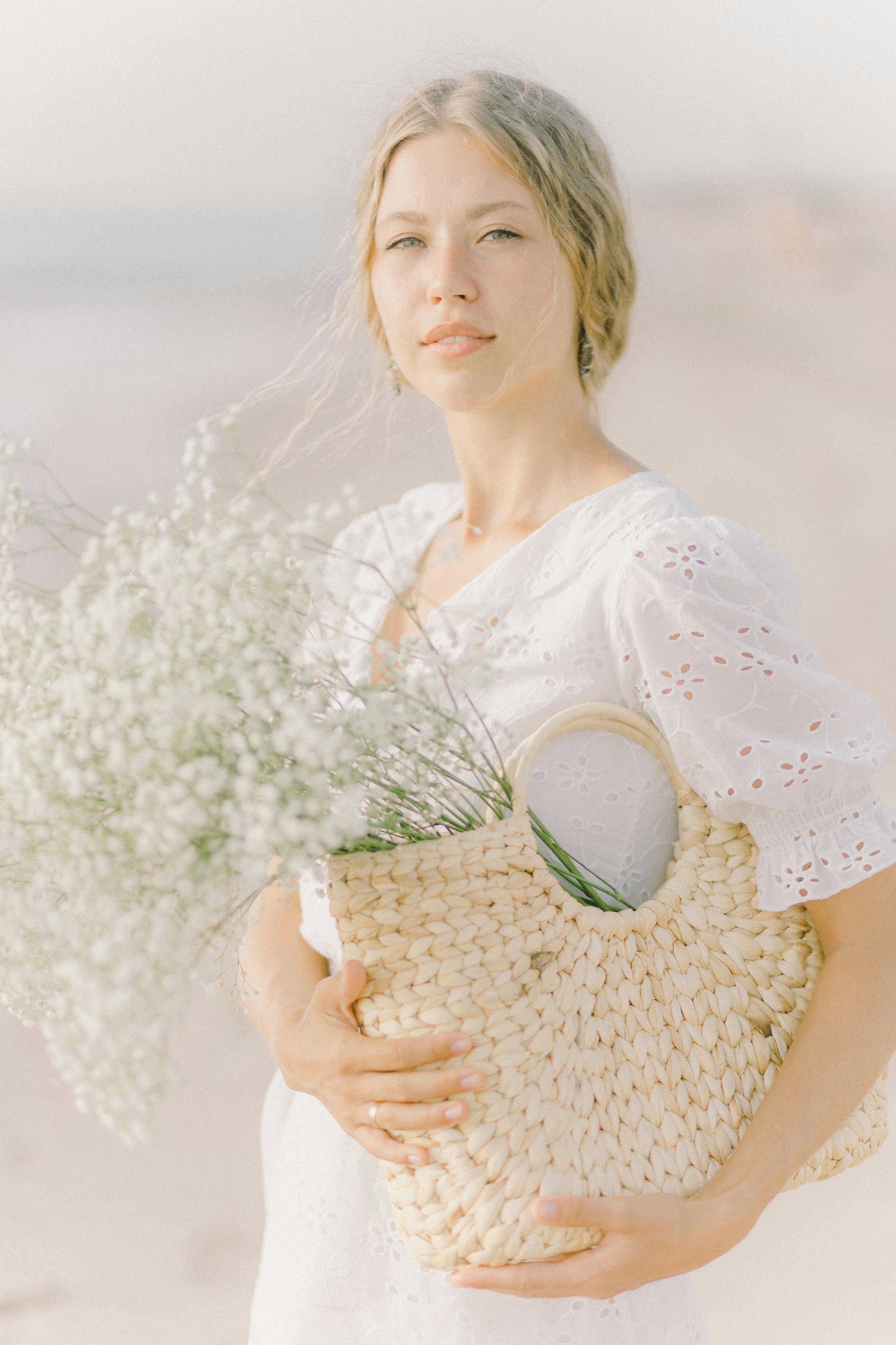 woman in white dress holding basket of flowers