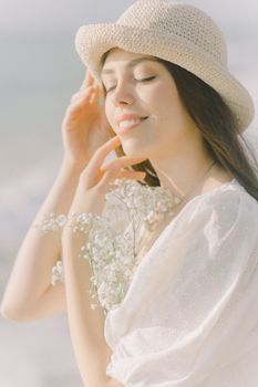 一名年轻女子戴着太阳帽、穿着白色连衣裙，在海滩上享受着宁静的时刻